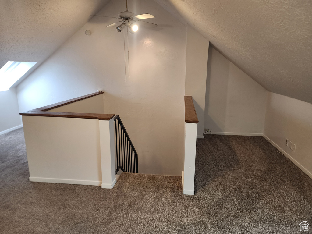 Additional living space with carpet flooring, vaulted ceiling, a textured ceiling, and baseboards