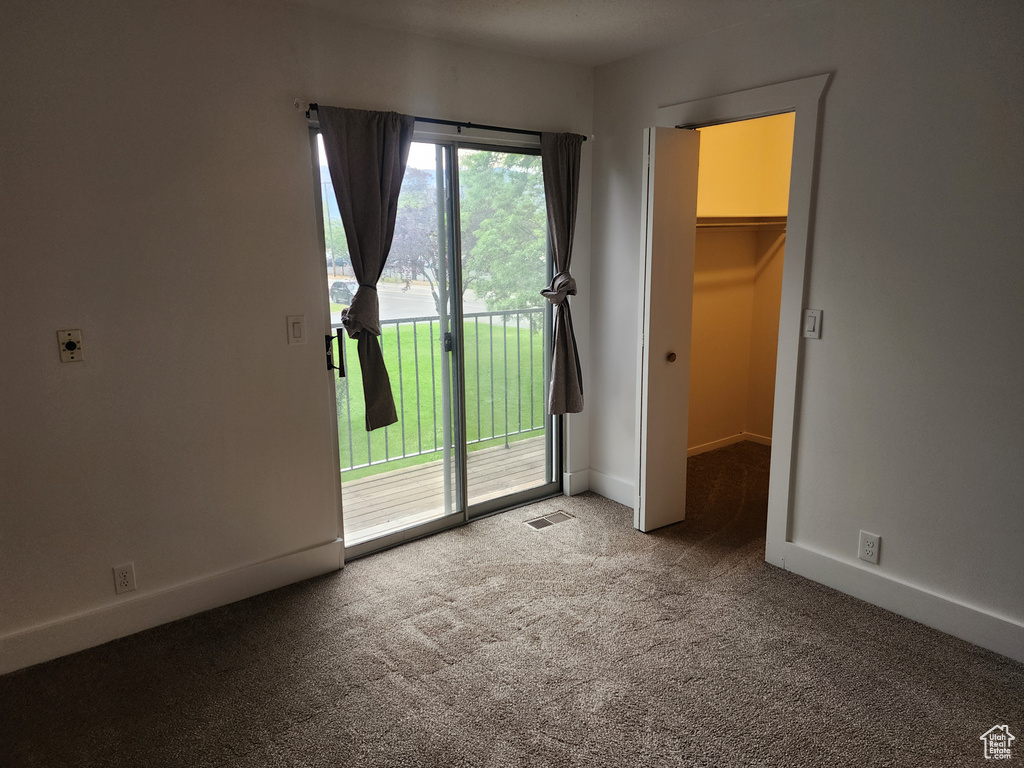 Unfurnished bedroom featuring access to outside, multiple windows, carpet, and baseboards