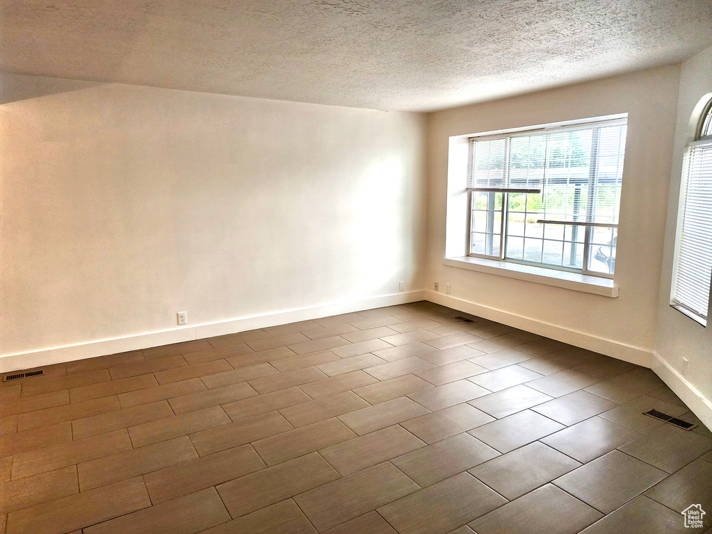 Unfurnished room with a textured ceiling and baseboards