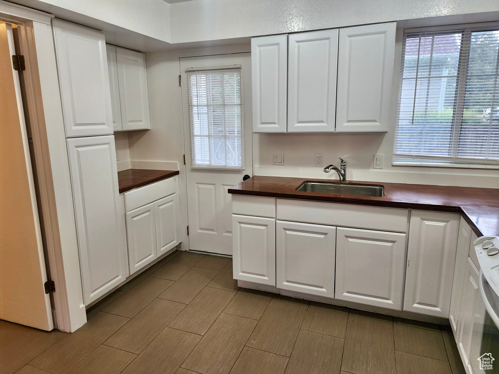 Kitchen with range, white cabinetry, and healthy amount of natural light