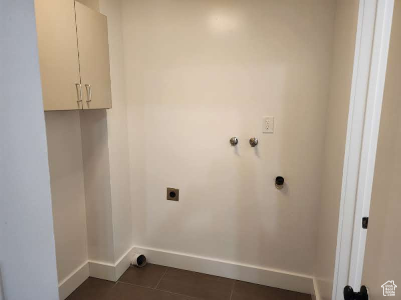 Laundry room with electric dryer hookup, cabinet space, baseboards, washer hookup, and dark tile patterned floors