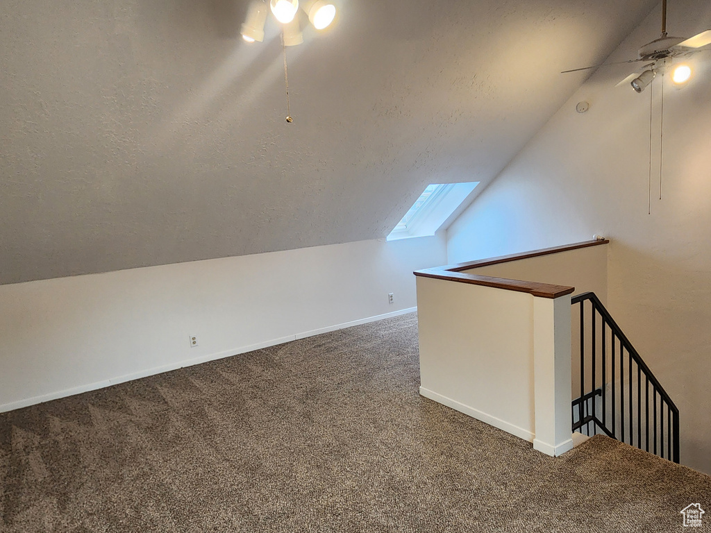 Bonus room with ceiling fan, vaulted ceiling, a skylight, carpet floors, and a textured ceiling