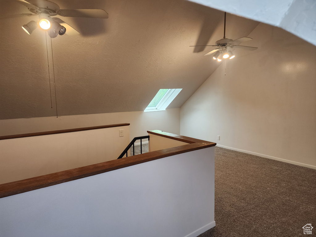 Additional living space with ceiling fan, lofted ceiling, a skylight, carpet floors, and baseboards