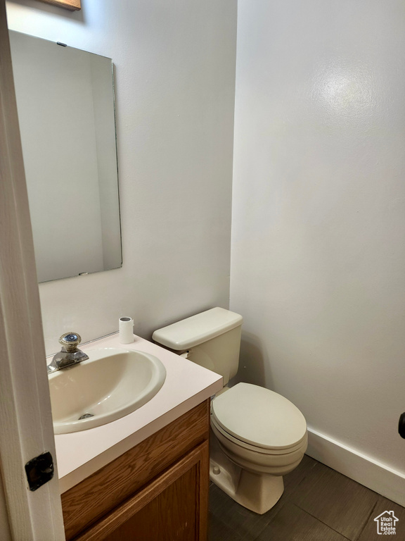 Bathroom featuring toilet, vanity, wood finished floors, and baseboards
