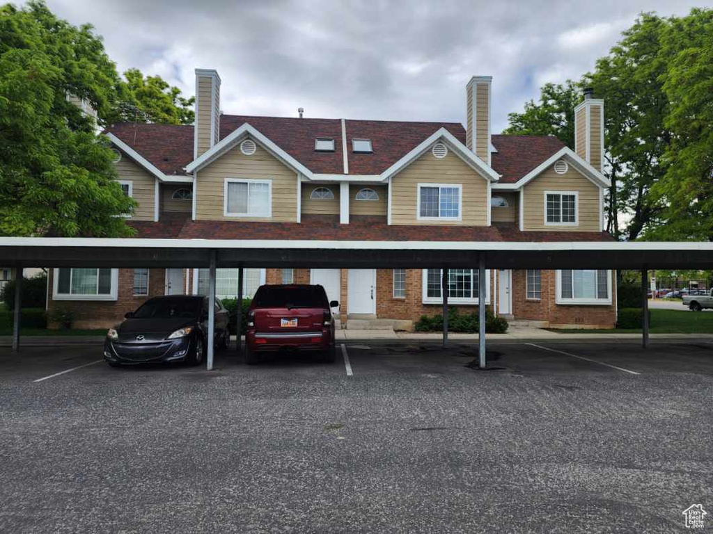 Rear view of property featuring brick siding, a chimney, and covered parking