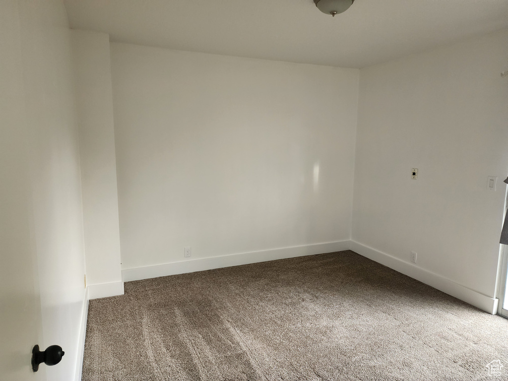 Carpeted spare room featuring baseboards