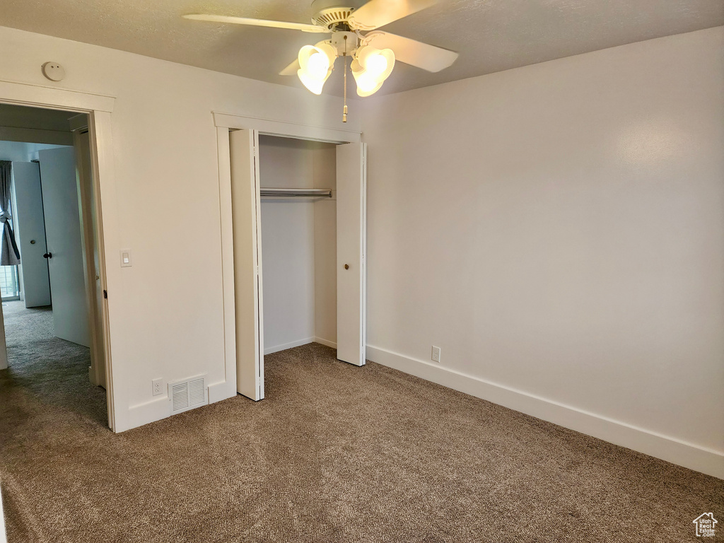 Unfurnished bedroom featuring carpet flooring, a closet, baseboards, and ceiling fan