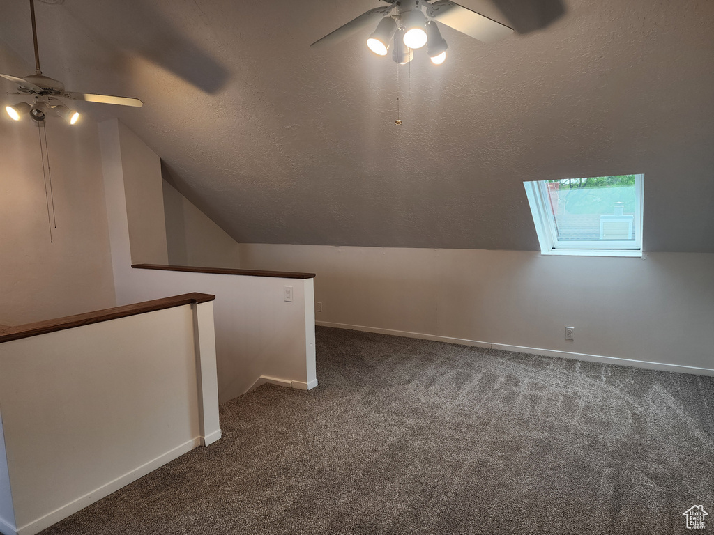 Additional living space featuring a ceiling fan, dark carpet, vaulted ceiling, and baseboards