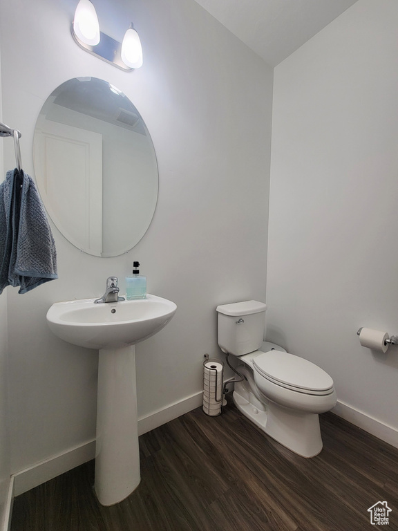 Half bath with wood finished floors, toilet, and baseboards