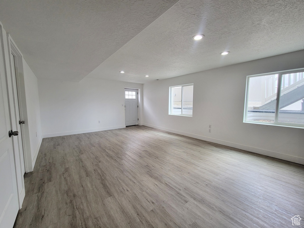 Unfurnished room featuring wood finished floors, a textured ceiling, baseboards, and recessed lighting