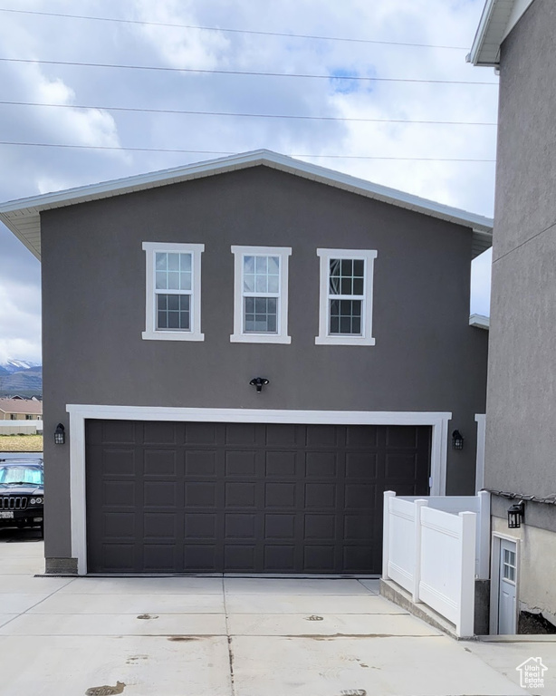 View of front of property with a garage, stucco siding, and concrete driveway
