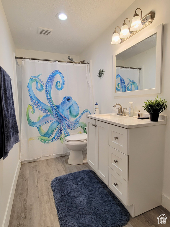 Full bathroom featuring wood finished floors, vanity, toilet, baseboards, and recessed lighting