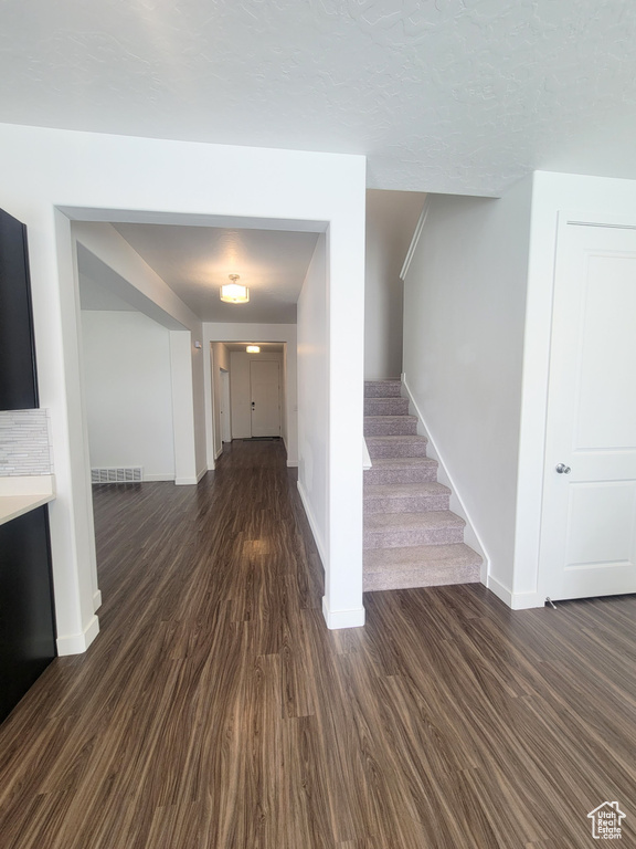Corridor with baseboards, dark wood-style flooring, and stairs