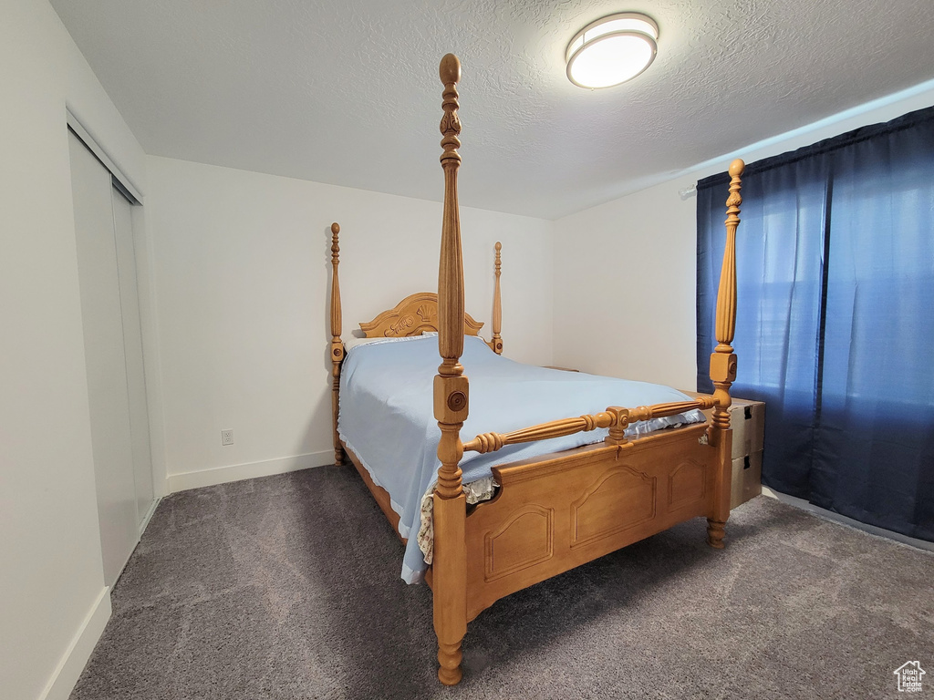 Carpeted bedroom featuring a textured ceiling and baseboards