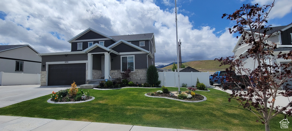 View of front facade with stone siding, concrete driveway, stucco siding, and a garage