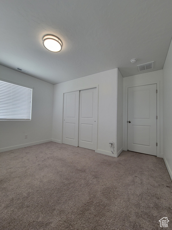 Unfurnished bedroom with carpet flooring, baseboards, and a closet