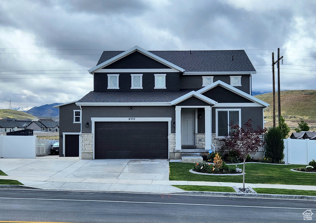 View of front of house featuring stucco siding, a garage, stone siding, and driveway