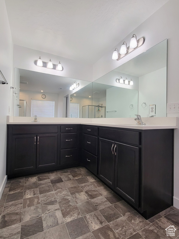 Bathroom featuring stone finish flooring, double vanity, and a shower