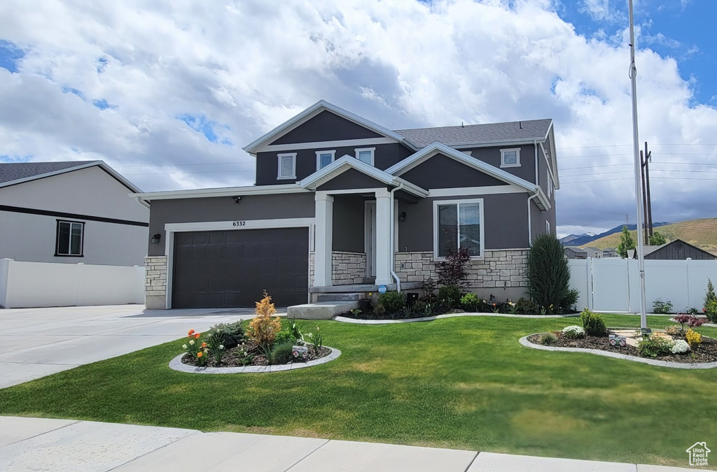 Craftsman-style house with stone siding, stucco siding, and driveway