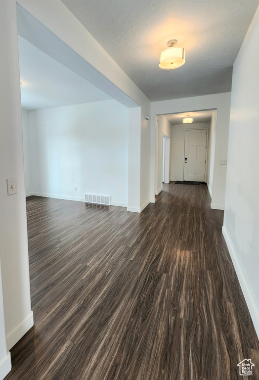 Empty room featuring baseboards and dark wood finished floors