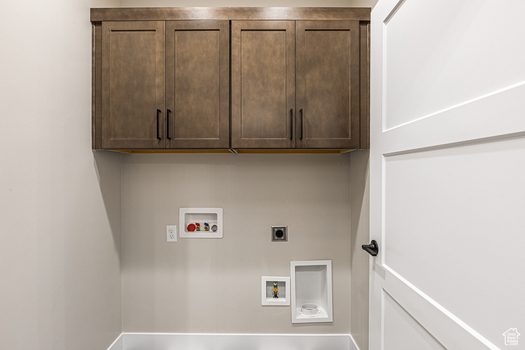 Washroom featuring electric dryer hookup, hookup for a washing machine, and cabinet space