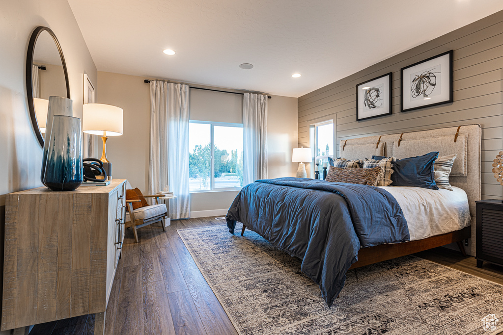 Bedroom featuring dark wood-style flooring, wooden walls, recessed lighting, and baseboards