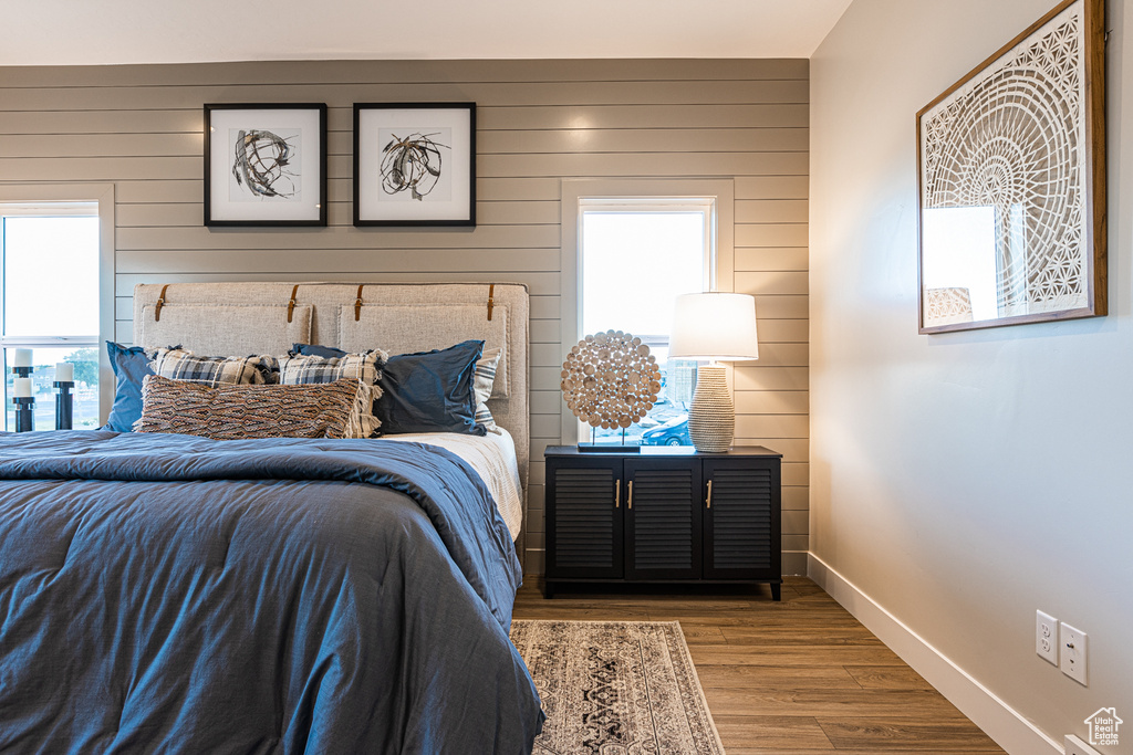 Bedroom with wooden walls, wood finished floors, and baseboards