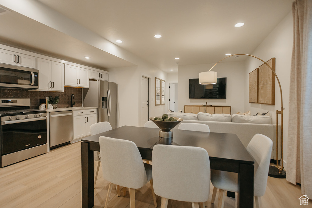 Dining area with light wood-type flooring and recessed lighting