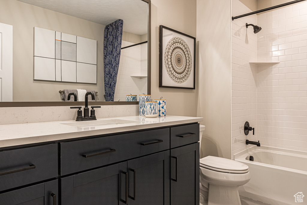 Bathroom featuring toilet, vanity, and  shower combination