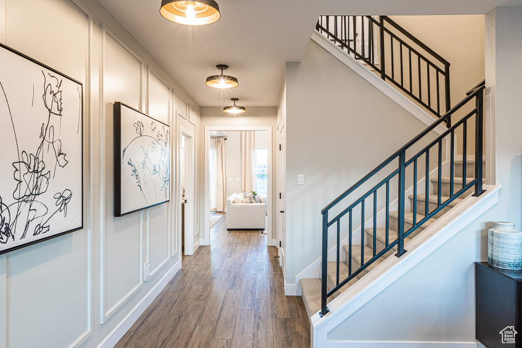 Foyer featuring dark wood-style flooring, stairs, and baseboards