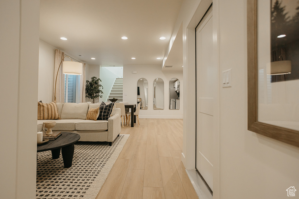 Living room with stairway, light wood finished floors, and recessed lighting