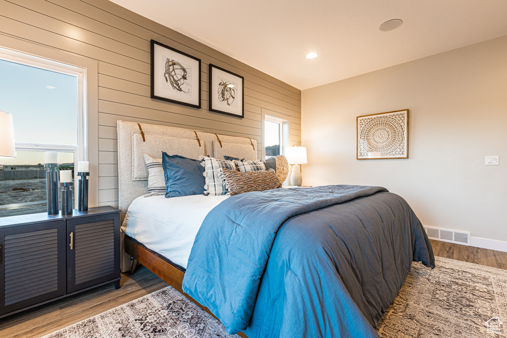 Bedroom with light wood-type flooring, wooden walls, baseboards, and recessed lighting