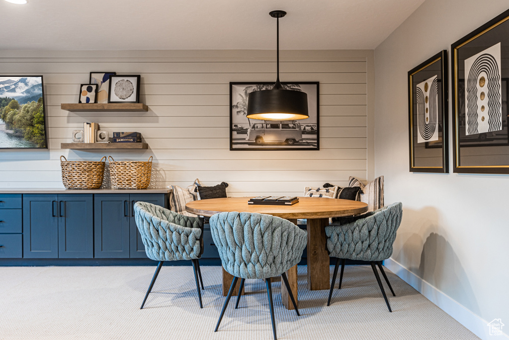 Dining space featuring light carpet, baseboards, wood walls, and breakfast area
