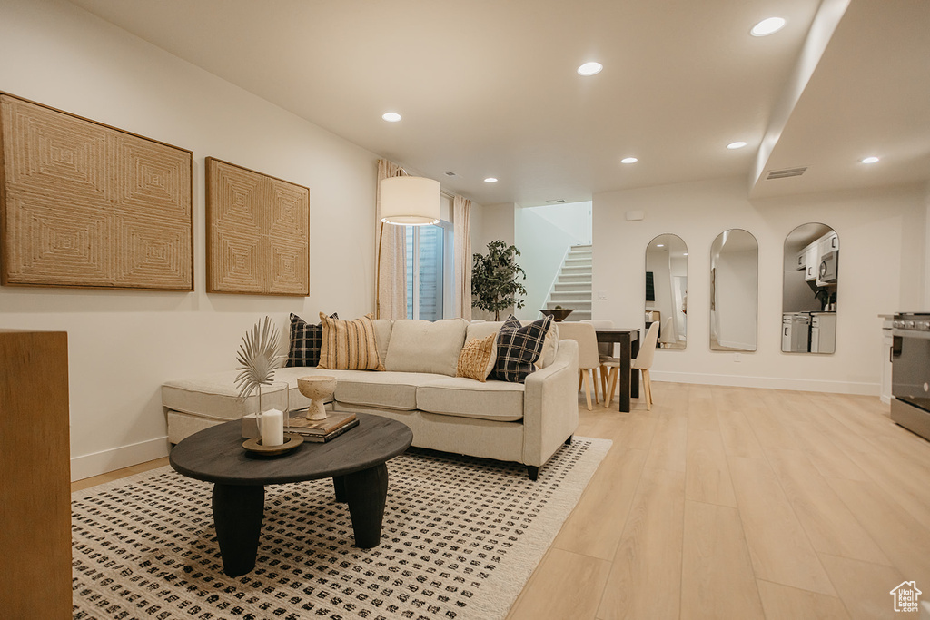 Living area featuring stairs, recessed lighting, light wood-style floors, and baseboards
