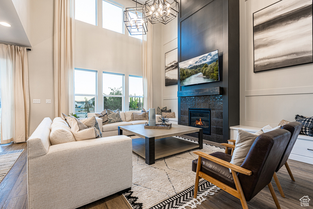 Living area with a towering ceiling, wood finished floors, a tile fireplace, and a chandelier