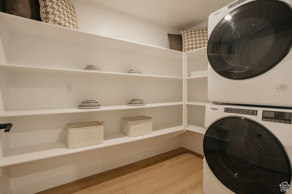 Washroom featuring stacked washing machine and dryer and light wood-style flooring