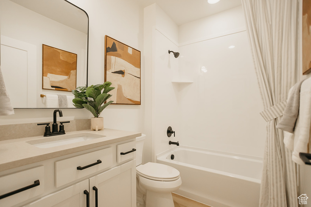 Bathroom featuring toilet, shower / tub combo with curtain, and vanity