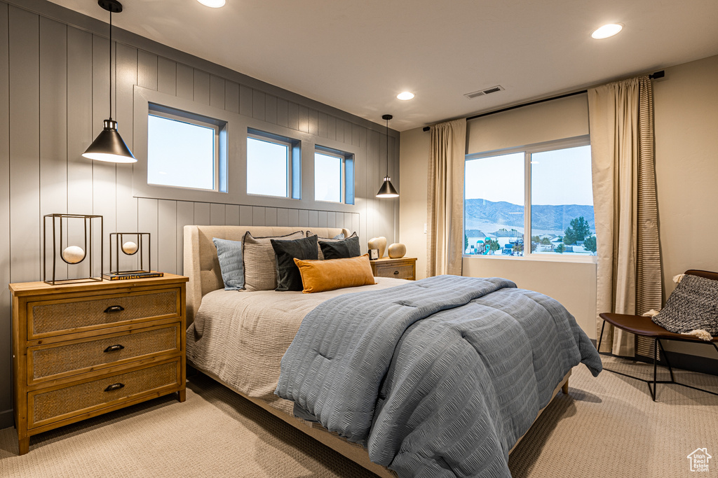 Bedroom featuring light carpet, recessed lighting, a mountain view, and a decorative wall