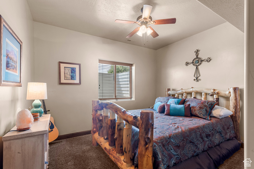 Carpeted bedroom with baseboards, ceiling fan, and a textured ceiling