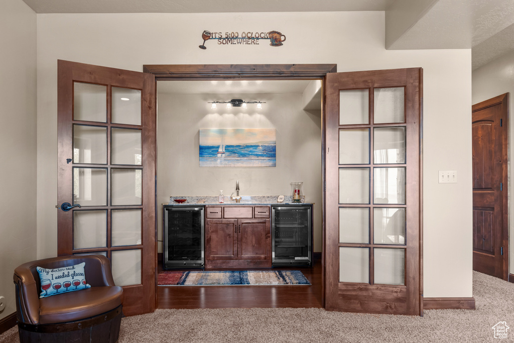 Indoor dry bar featuring beverage cooler, carpet floors, and baseboards