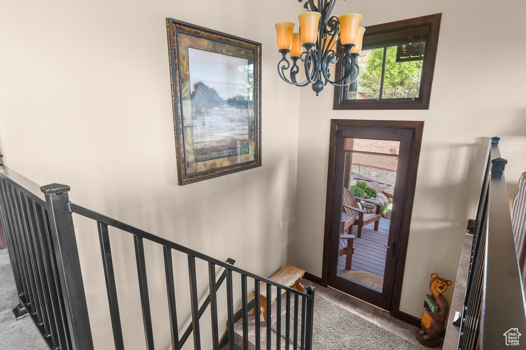 Carpeted entryway featuring a chandelier and baseboards