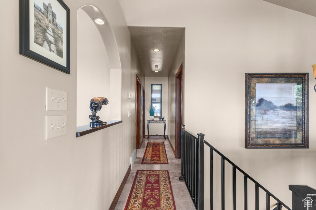 Hall featuring an upstairs landing, baseboards, arched walkways, and recessed lighting