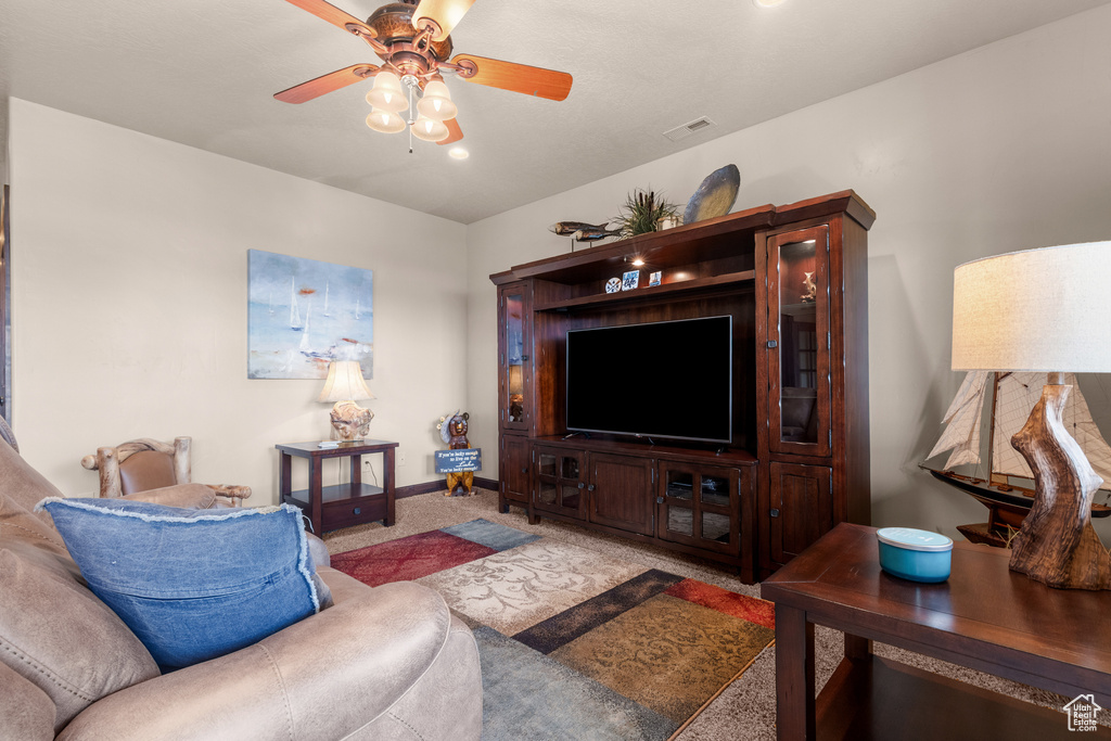 Living room featuring carpet floors, ceiling fan, and baseboards