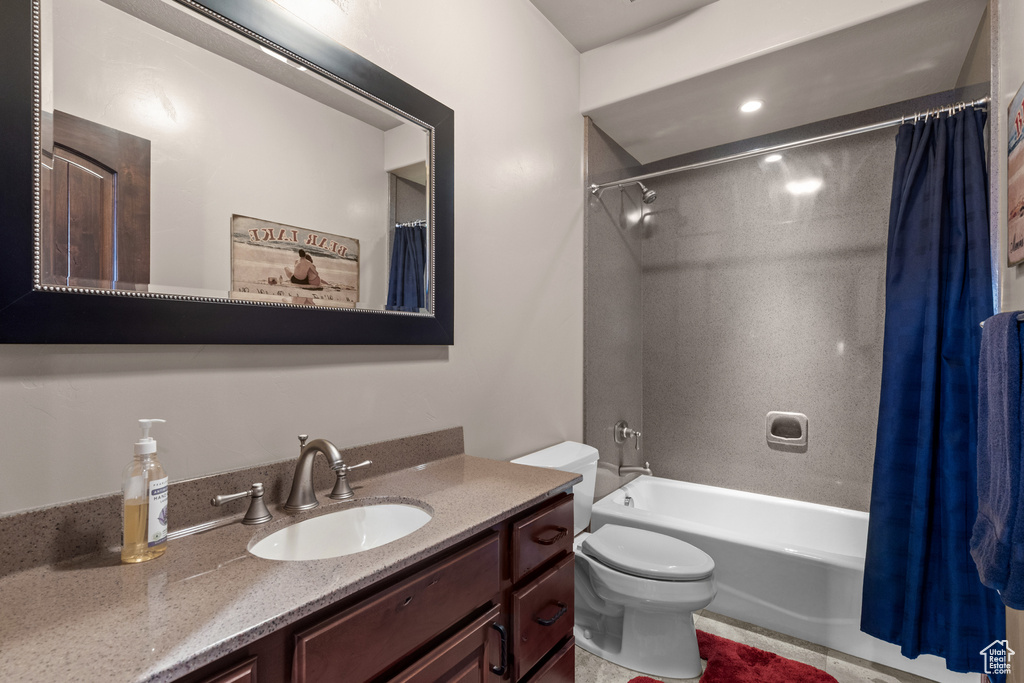 Bathroom featuring shower / bath combo with shower curtain, toilet, and vanity