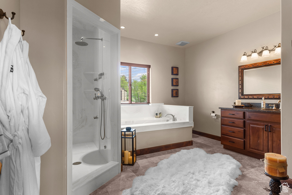 Bathroom with a stall shower, a bath, vanity, baseboards, and recessed lighting
