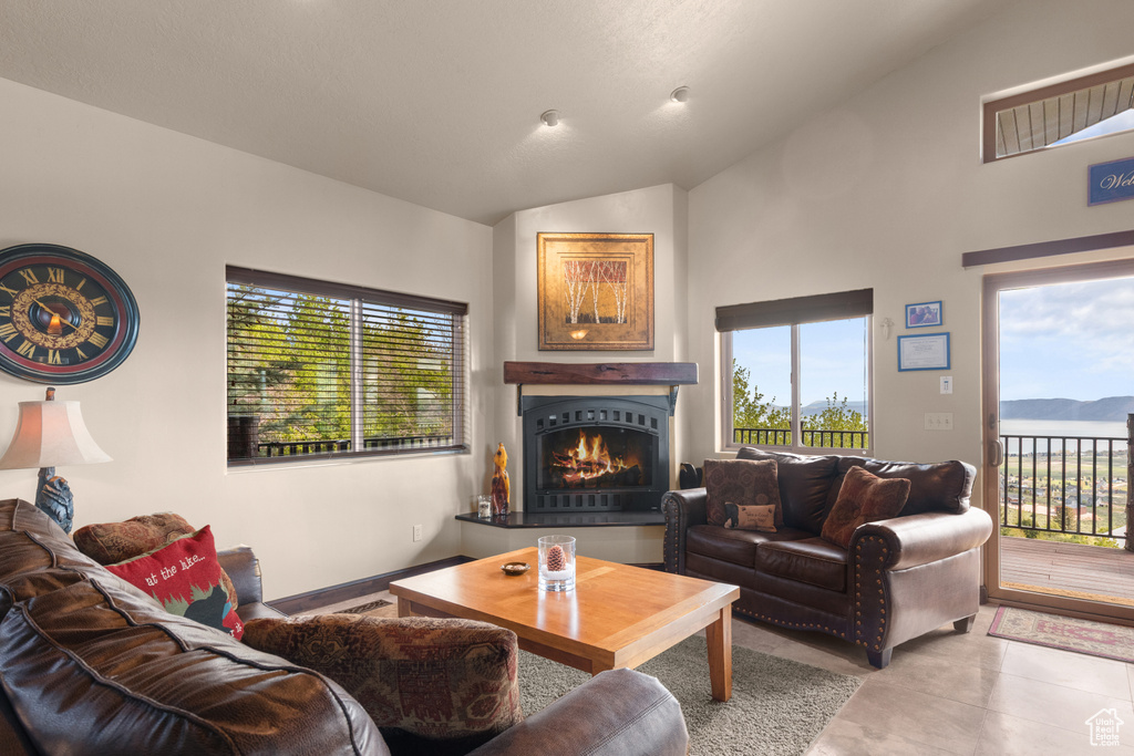 Living area with lofted ceiling, healthy amount of natural light, a warm lit fireplace, and a mountain view
