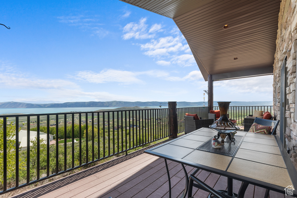 Deck with outdoor dining space and a water and mountain view