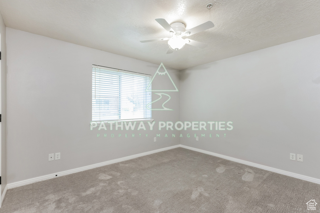 Unfurnished room with carpet floors, a ceiling fan, baseboards, and a textured ceiling
