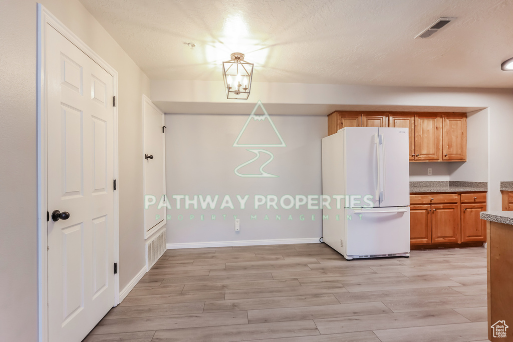 Kitchen featuring freestanding refrigerator, light wood-style floors, light countertops, and baseboards