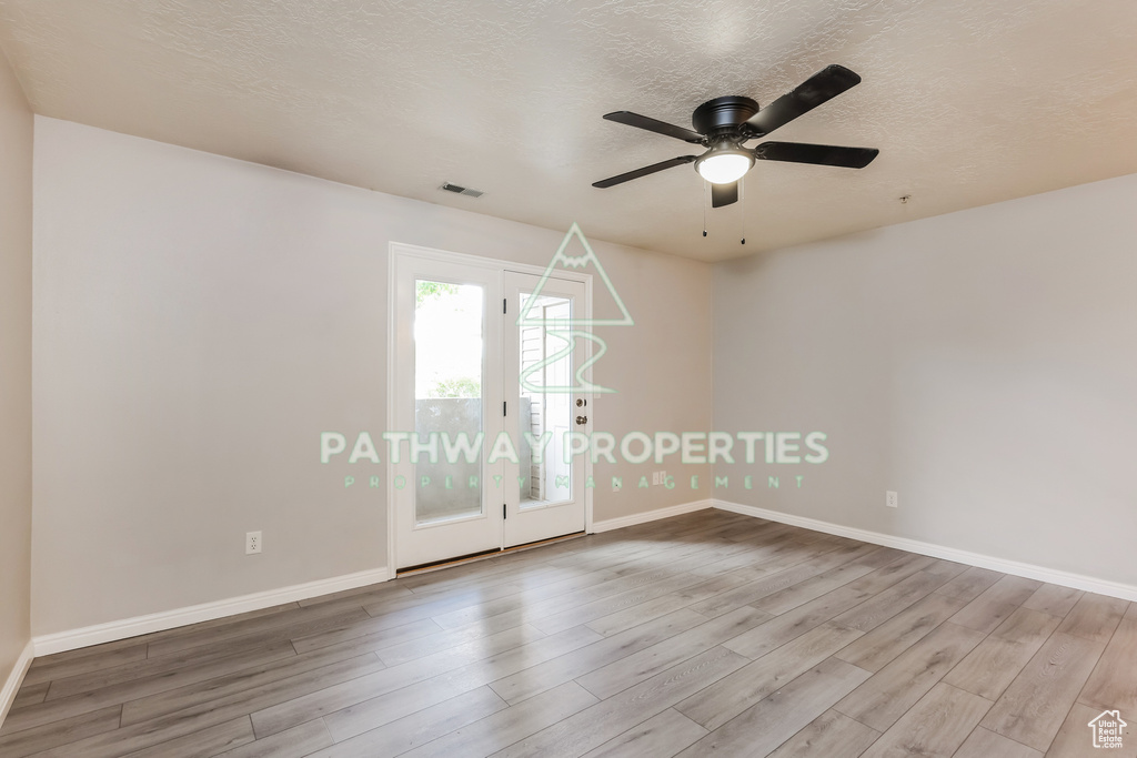 Spare room with wood finished floors, baseboards, a ceiling fan, and a textured ceiling